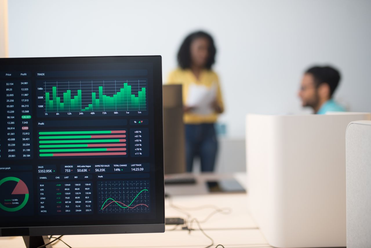 The Art of Drawing Readers In: Your attractive post title goes here Modern office with financial trading screens and a diverse team discussing strategies.